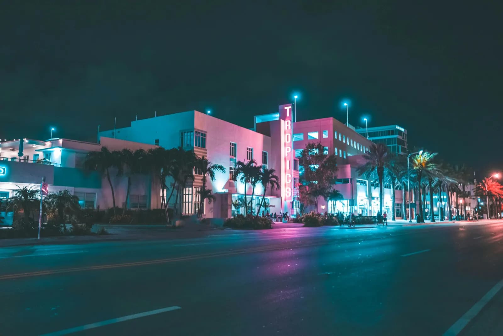 Gece Ocean Drive: palmiyelerin ardında neon tabelalı art deco otel cepheleri ve boş cadde.